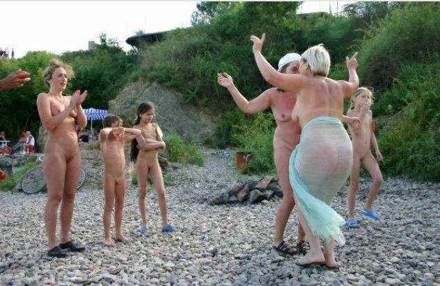 The company of nudists dances on a beach